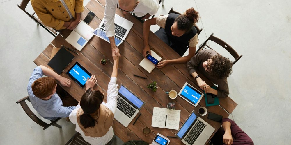 Photo by fauxels Top view of a diverse team collaborating in an office setting with laptops and tablets, promoting cooperation.